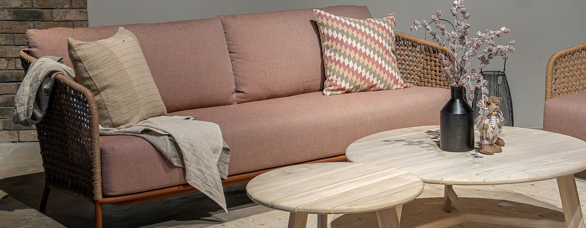 A three-seater sofa features natural wood-coloured straw weave detailing and terracttoa fabric